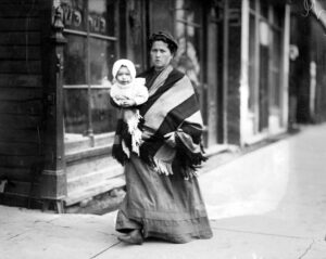 Woman walking down street with baby in her arms